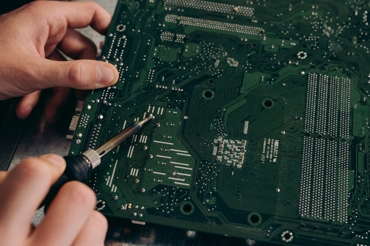 Hands soldering a motherboard with precision demonstrating electronics repair skills.
